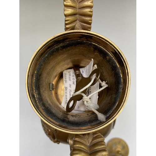 2918 - A French Empire ormolu cased mantel clock, of urn form, the covered rim applied with two winged cher... 