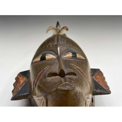 297 - An African carved tribal mask, the horned figure with painted decoration surmounted by a bird, heigh... 