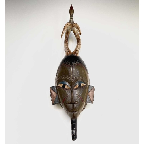 297 - An African carved tribal mask, the horned figure with painted decoration surmounted by a bird, heigh... 