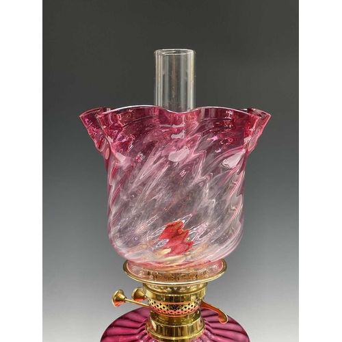 300 - A Victorian cranberry glass and brass oil lamp, with spiral fluted shade and column support, overall... 