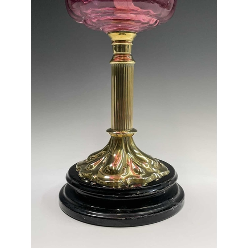 300 - A Victorian cranberry glass and brass oil lamp, with spiral fluted shade and column support, overall... 