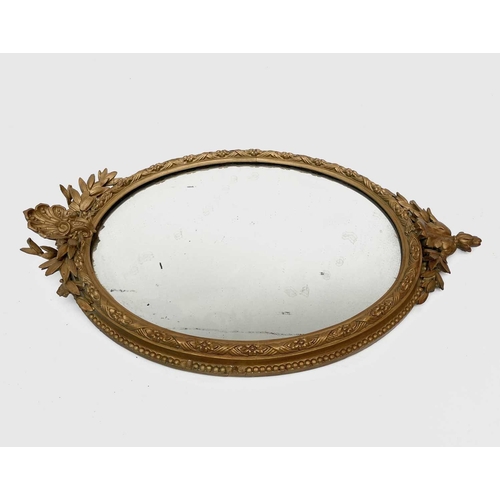 3016 - A Victorian oval gilt wall mirror, the gesso frame moulded with ribbons and flowerheads, height 84cm... 