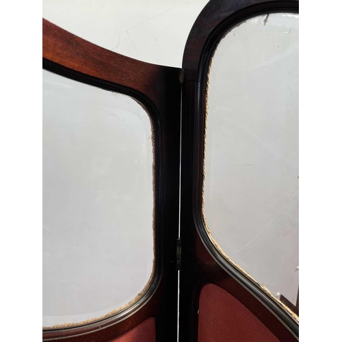 3033 - A late Victorian mahogany four-fold dressing screen, the upholstered panels with glazed upper parts.... 