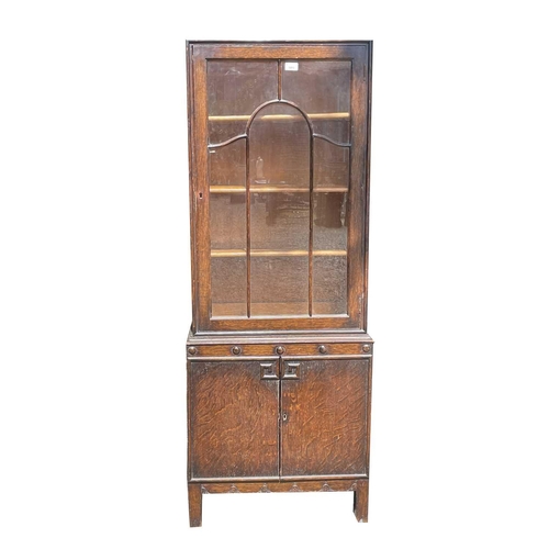 3053 - A 1930's oak bookcase/display cabinet, enclosing adjustable shelves, with two cupboard doors below, ... 