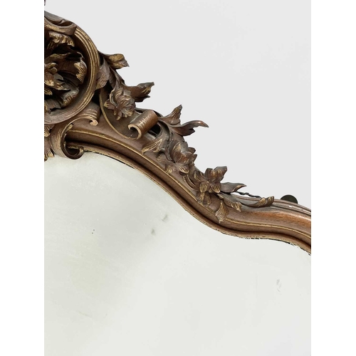 3087 - A late 19th century French walnut and parcel gilt wall mirror, with floral carved cresting and base,... 