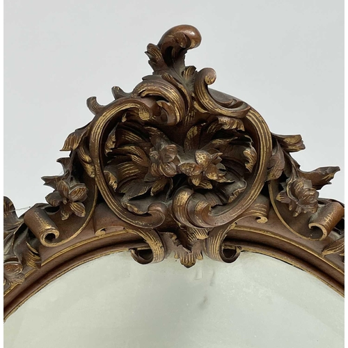 3087 - A late 19th century French walnut and parcel gilt wall mirror, with floral carved cresting and base,... 