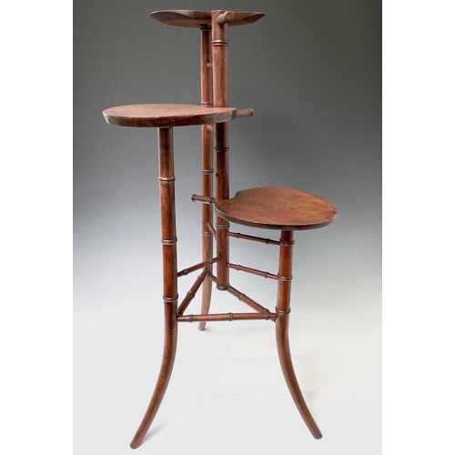 3088 - An Arts and Crafts mahogany stand, with three staggered leaf shape tiers and simulated bamboo turned... 