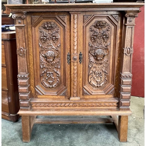 3096 - A Continental oak side cabinet, late 19th century, the two doors carved with cherub masks, fruit lad... 