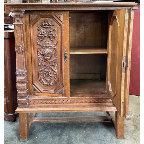 3096 - A Continental oak side cabinet, late 19th century, the two doors carved with cherub masks, fruit lad... 