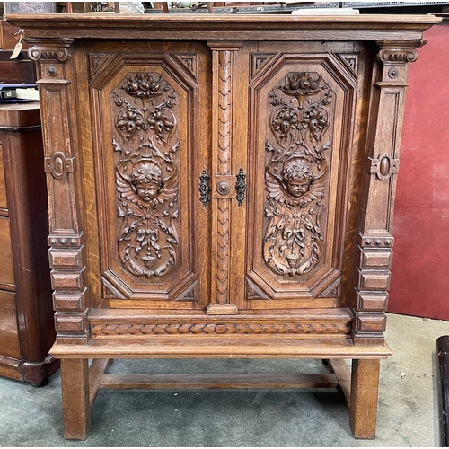 3096 - A Continental oak side cabinet, late 19th century, the two doors carved with cherub masks, fruit lad... 