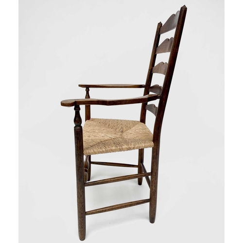 3104 - Robin Nance, An Arts and Crafts elbow ladder back elbow chair, with rush seat and turned supports, h... 