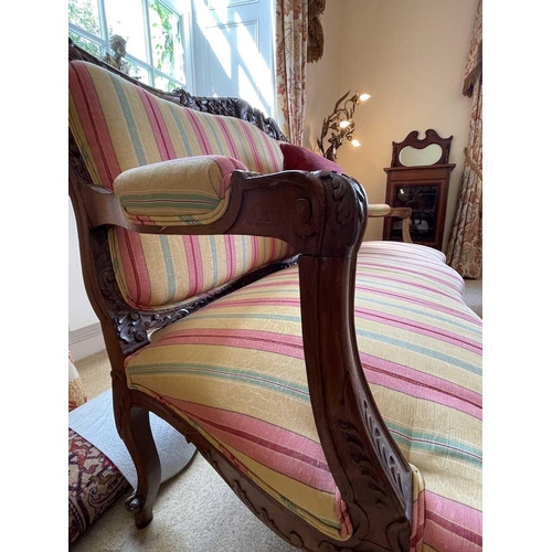 3112 - A French walnut settee, circa 1900, the frame deeply carved with scrolling foliage and flowers, on a... 