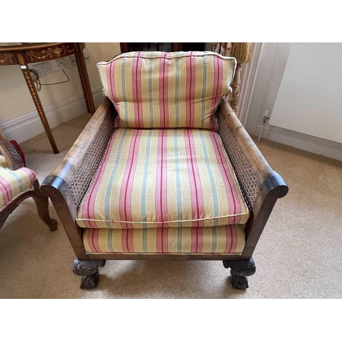 3113 - A pair of beech and walnut framed Bergere armchairs, circa 1920, with caned backs and arms, on carve... 