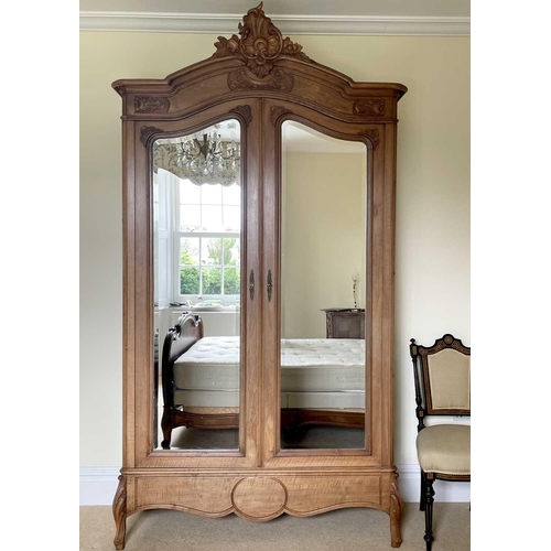 3132 - A French walnut armoire, late 19th century, with carved decoration, the two mirror doors enclosing a... 