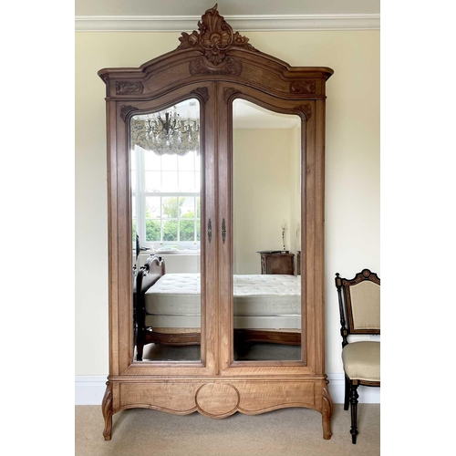 3132 - A French walnut armoire, late 19th century, with carved decoration, the two mirror doors enclosing a... 