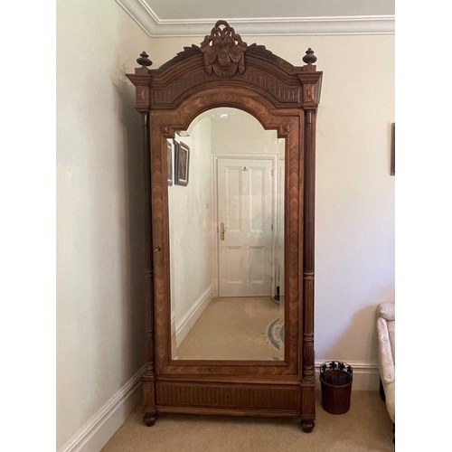 3139 - A French rosewood wardrobe, late 19th century, with arched and carved top, the mirrored door enclosi... 