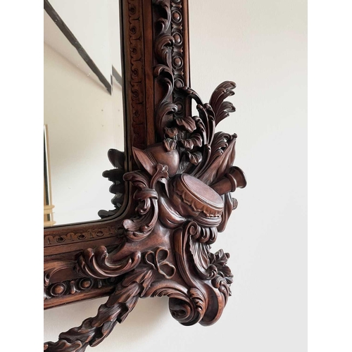 3143 - A mahogany ornate wall mirror, later 20th century, the frame carved with figures, dragons and milita... 