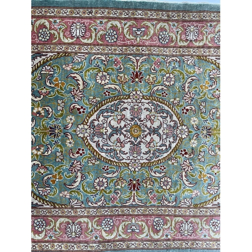 3202 - A Turkish silk rug, the pale blue field with an oval ivory medallion with scrolling flowering leafy ... 