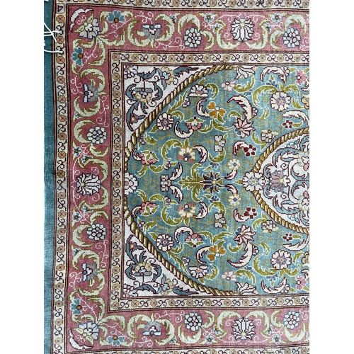 3202 - A Turkish silk rug, the pale blue field with an oval ivory medallion with scrolling flowering leafy ... 