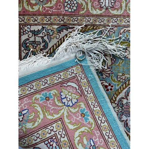 3202 - A Turkish silk rug, the pale blue field with an oval ivory medallion with scrolling flowering leafy ... 