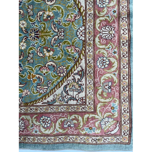 3202 - A Turkish silk rug, the pale blue field with an oval ivory medallion with scrolling flowering leafy ... 