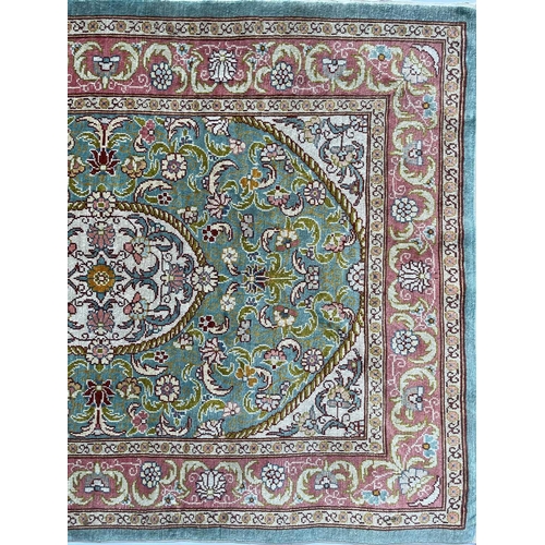 3202 - A Turkish silk rug, the pale blue field with an oval ivory medallion with scrolling flowering leafy ... 