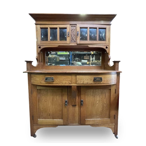 3206 - An Arts & Crafts oak sideboard, the upper part fitted with two glazed doors, the base with two bow f... 