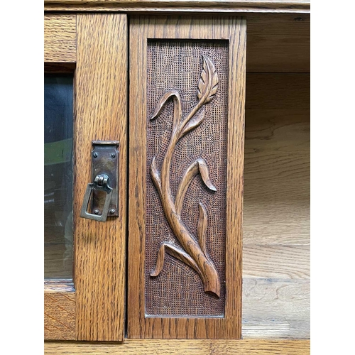 3206 - An Arts & Crafts oak sideboard, the upper part fitted with two glazed doors, the base with two bow f... 