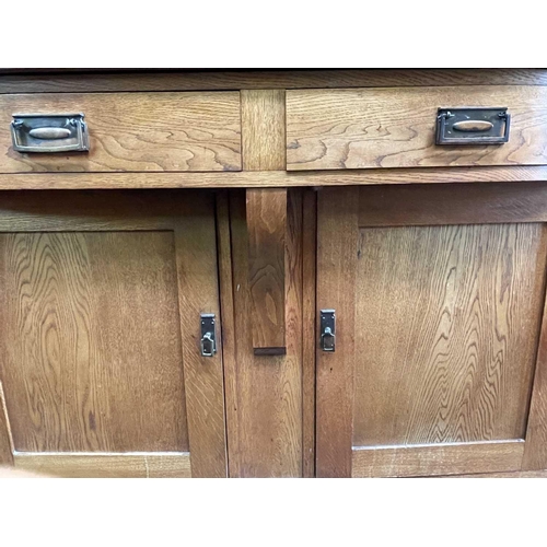 3206 - An Arts & Crafts oak sideboard, the upper part fitted with two glazed doors, the base with two bow f... 