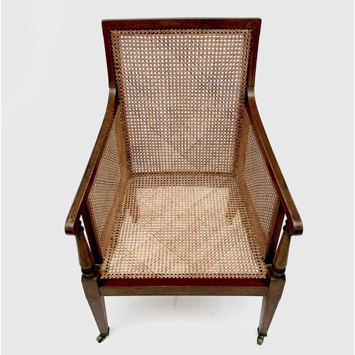 3207 - An Edwardian mahogany caned library armchair, with turned front supports on square legs and casters,... 