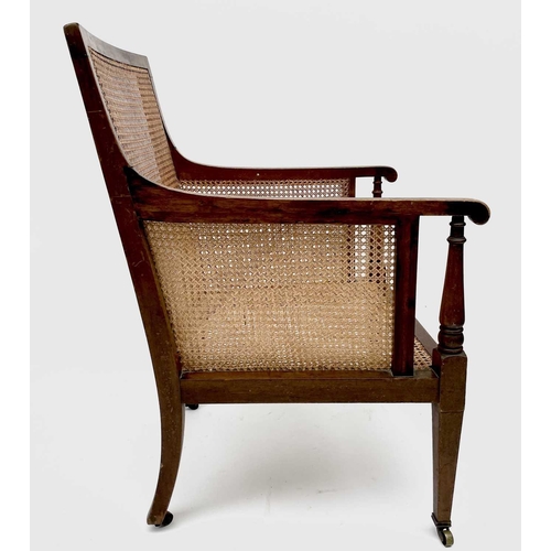 3207 - An Edwardian mahogany caned library armchair, with turned front supports on square legs and casters,... 