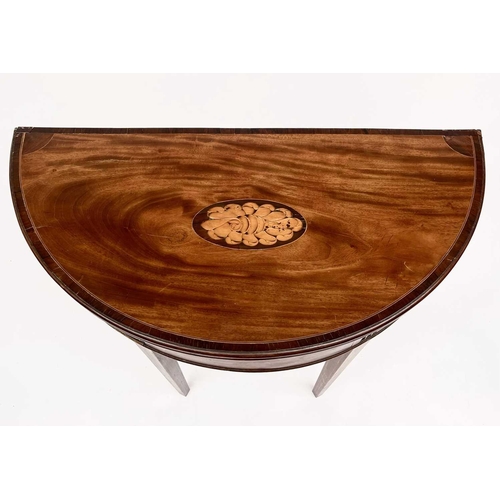 3217 - A George III mahogany demi lune fold over card table, the top with a shell inlaid oval panel and ros... 