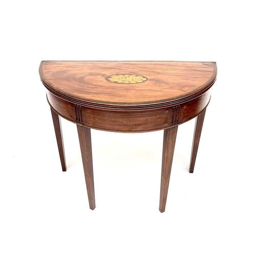 3217 - A George III mahogany demi lune fold over card table, the top with a shell inlaid oval panel and ros... 