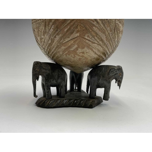 406 - An Indian carved coconut, on elephant stand, height 18cm, together with a carved ethnic figure etc (... 