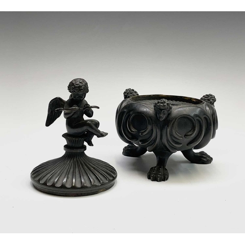 407 - A Regency bronze inkwell with cover, the lid surmounted by the figure of Cupid, the base cast with t... 