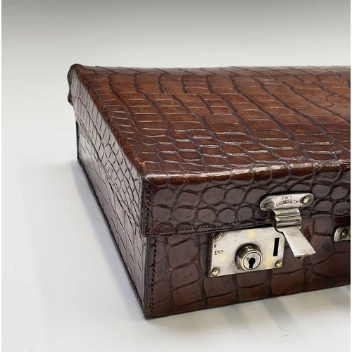 419 - An early 20th century crocodile skin briefcase with fitted interior, the silver plated lock plates m... 