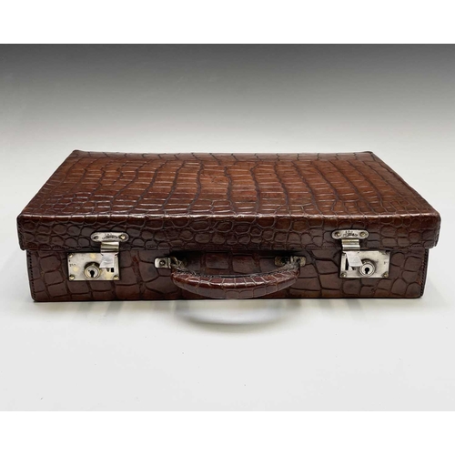 419 - An early 20th century crocodile skin briefcase with fitted interior, the silver plated lock plates m... 