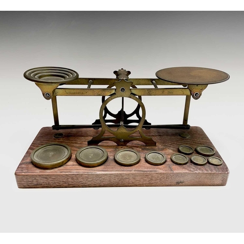 42 - A set of late Victorian Sampson Mordan & Co brass and oak postal scales, the base set with nine bras... 