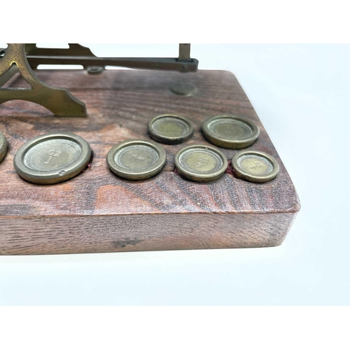 42 - A set of late Victorian Sampson Mordan & Co brass and oak postal scales, the base set with nine bras... 