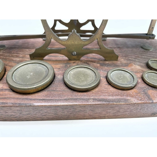 42 - A set of late Victorian Sampson Mordan & Co brass and oak postal scales, the base set with nine bras... 