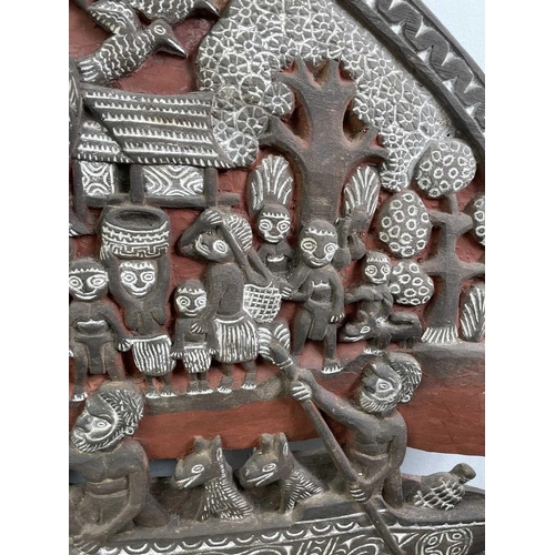 431 - An ethnic carved large plaque, decorated with figures and animals in a crocodile boat, with further ... 