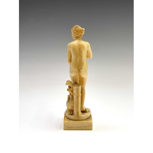 473 - A 19th century French carved ivory figure of Eve, standing beside cherubs playing on a dolphin, heig... 