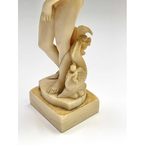 473 - A 19th century French carved ivory figure of Eve, standing beside cherubs playing on a dolphin, heig... 