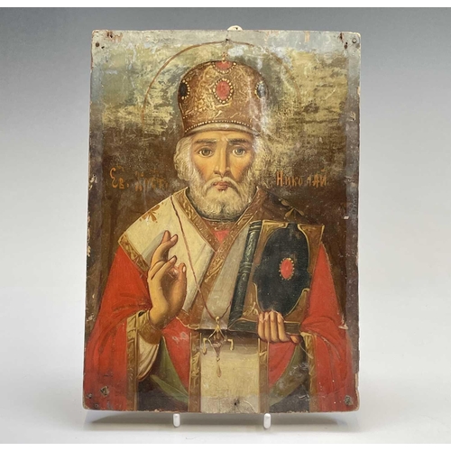 48 - A Russian softwood icon, circa 1900, painted with St Nicholas, holding a bible, 23cm X 16.5cm