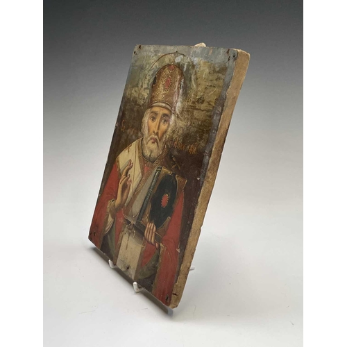 48 - A Russian softwood icon, circa 1900, painted with St Nicholas, holding a bible, 23cm X 16.5cm