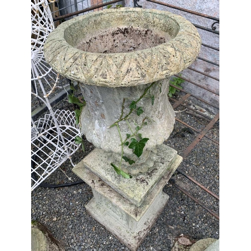 600 - A reconstituted stone garden urn of campana form, raised on an associated square plinth base, both h... 