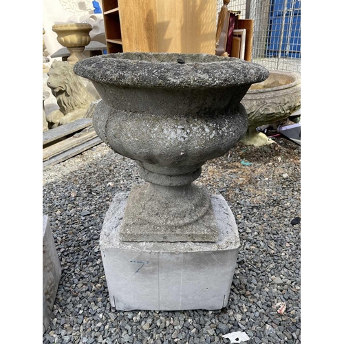 603 - A pair of composition garden urns on associated cast concrete stands. Overall height 63cm.