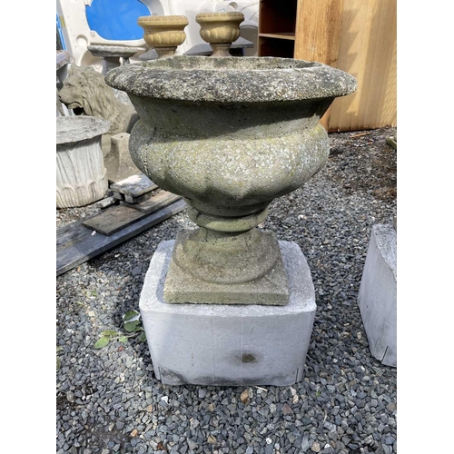 603 - A pair of composition garden urns on associated cast concrete stands. Overall height 63cm.