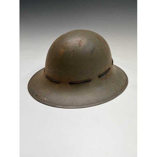 80 - A WWII steel helmet, painted khaki, the liner stamped BMB 1942, with webbing chin strap, together wi... 