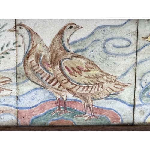 831 - A set of three 20th century ceramic tiles, handpainted with birds, framed. 19cm x 49cm.